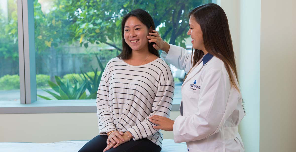 Doctor at the UH Cancer Center Patient Care Program examining a young woman.